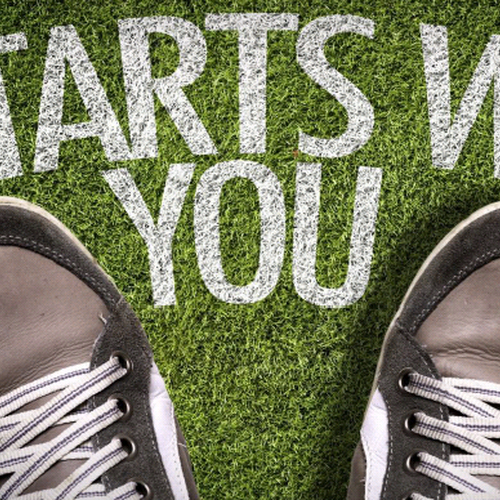 Schuhe auf einem grasigen Boden, Schriftzug "it starts with you"