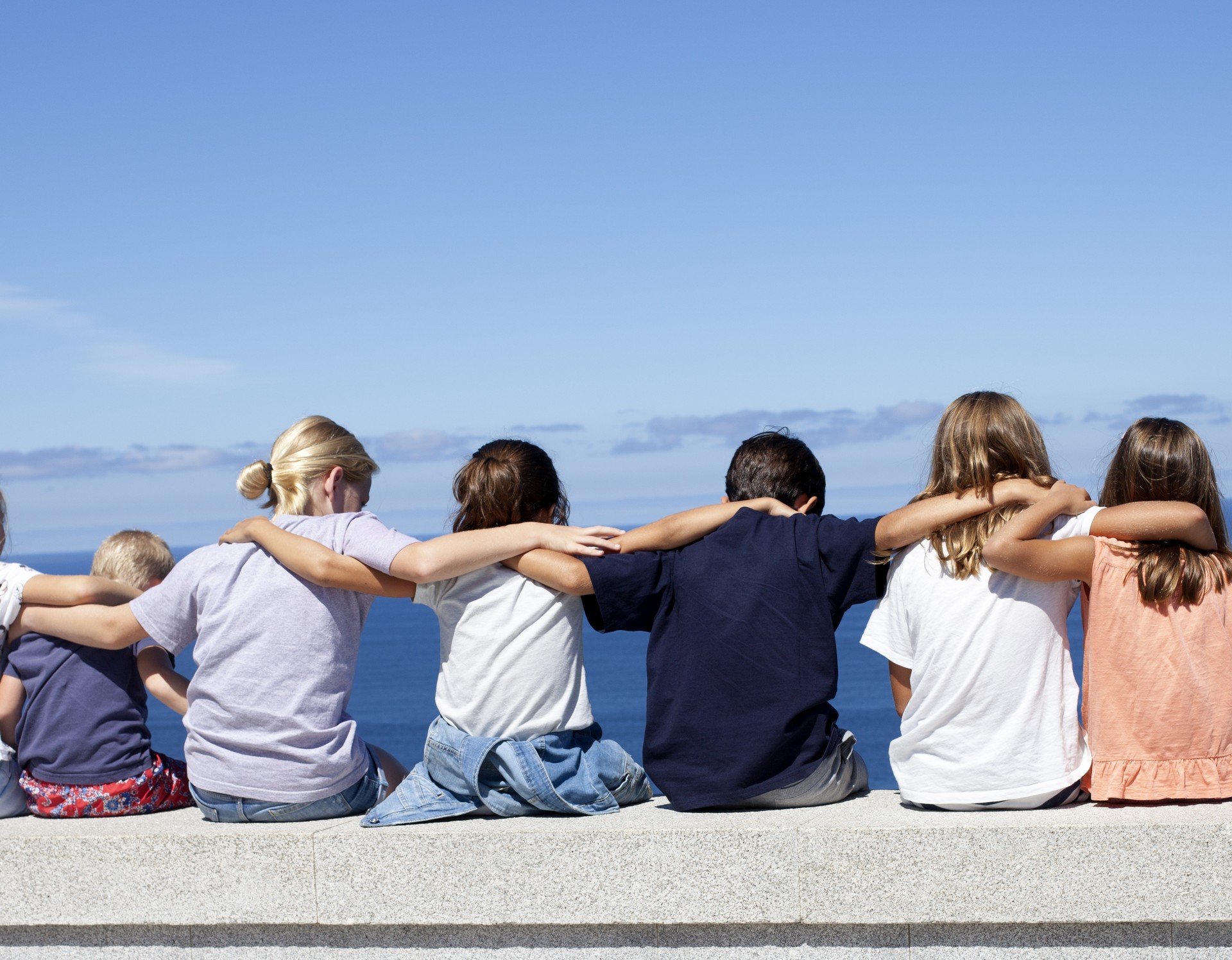 Kinder blicken aufs Meer und umarmen sich