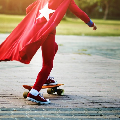 Kind im Superheldenkostüm auf Skateboard